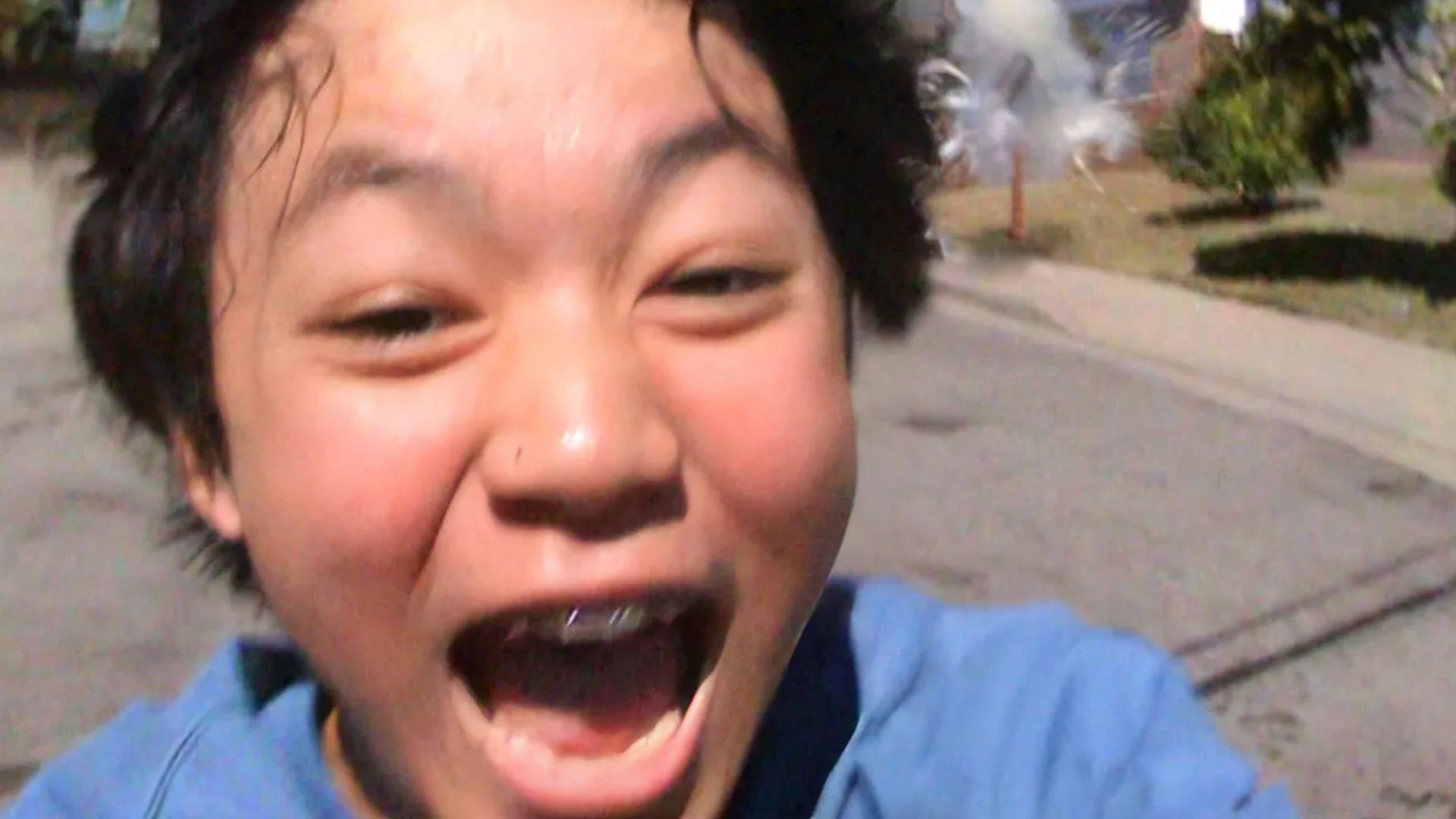 young boy outside taking selfie up close of face with mouth open joy 