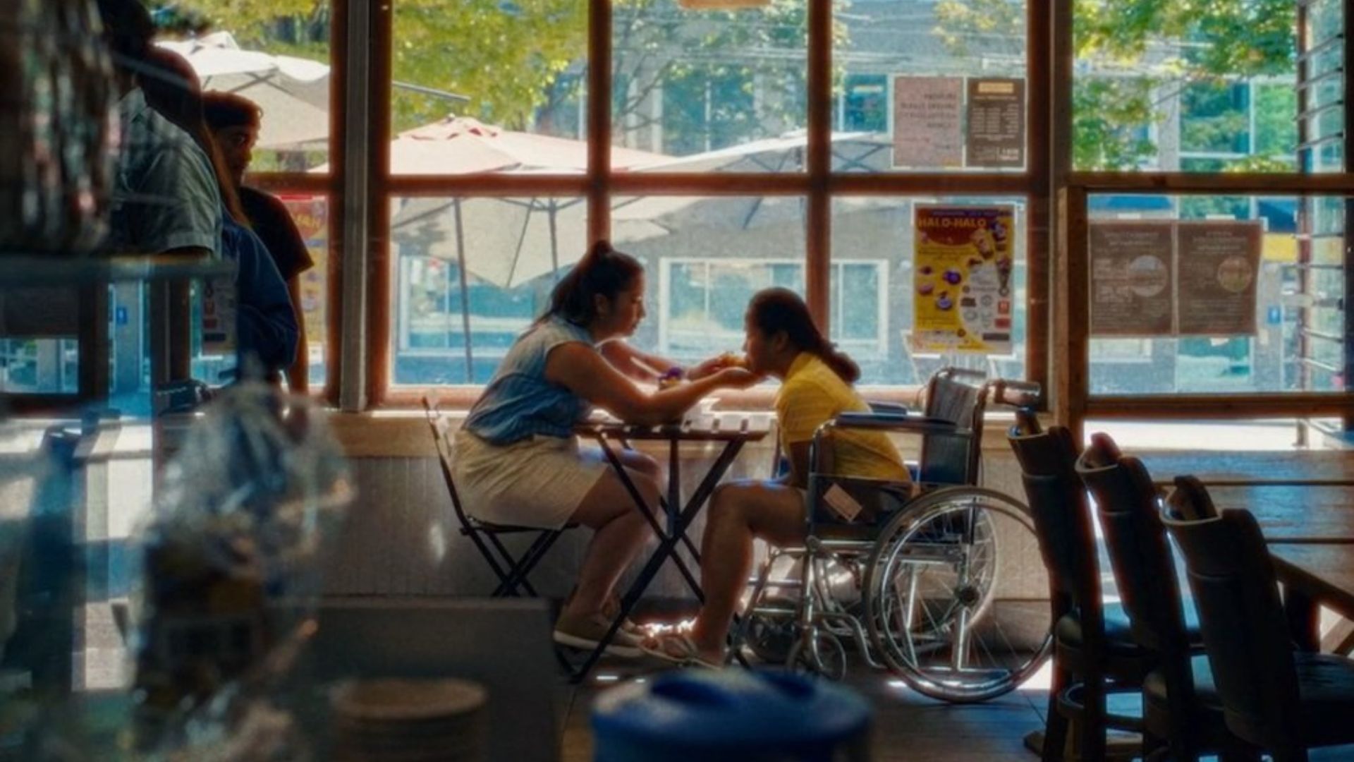 two women sitting at cafe table near window looking closely at each other
