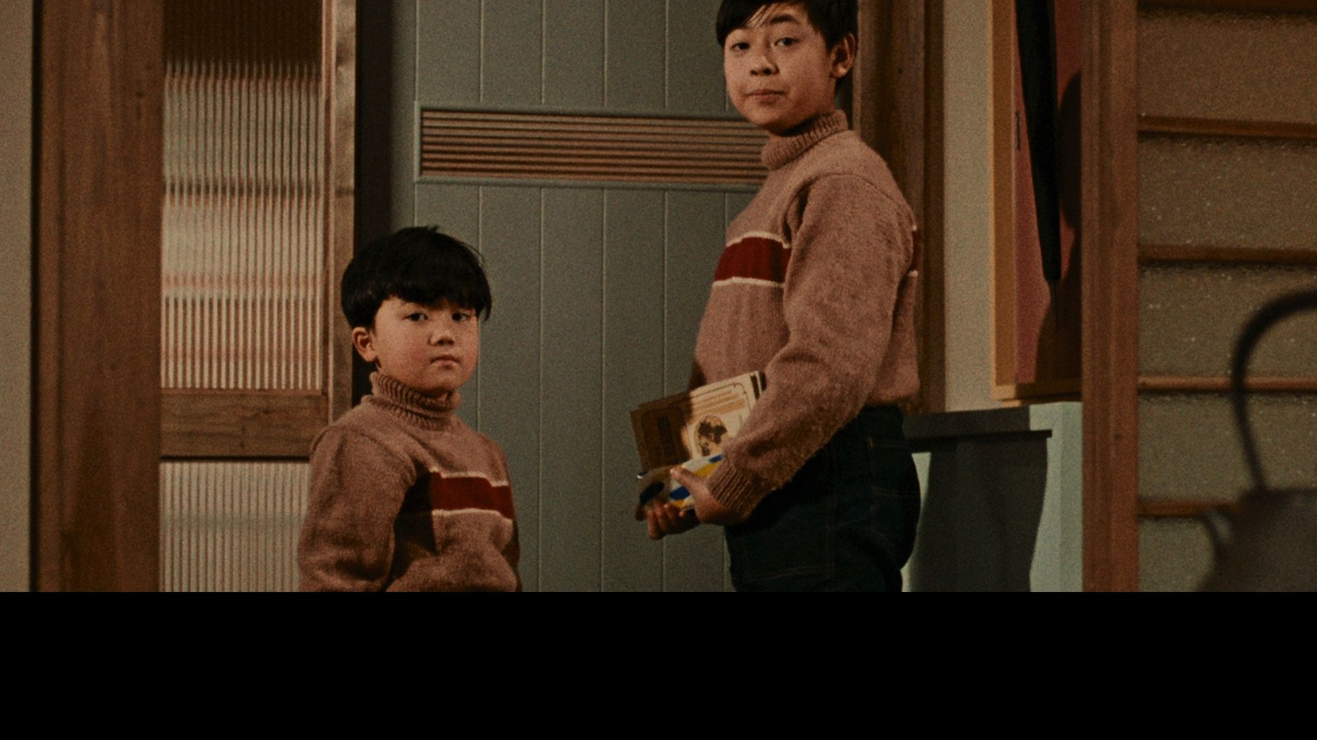 two young boys in sweaters holding books turning around