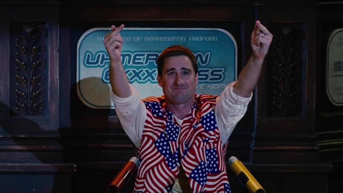 man in american flag jacket holding up two middle fingers