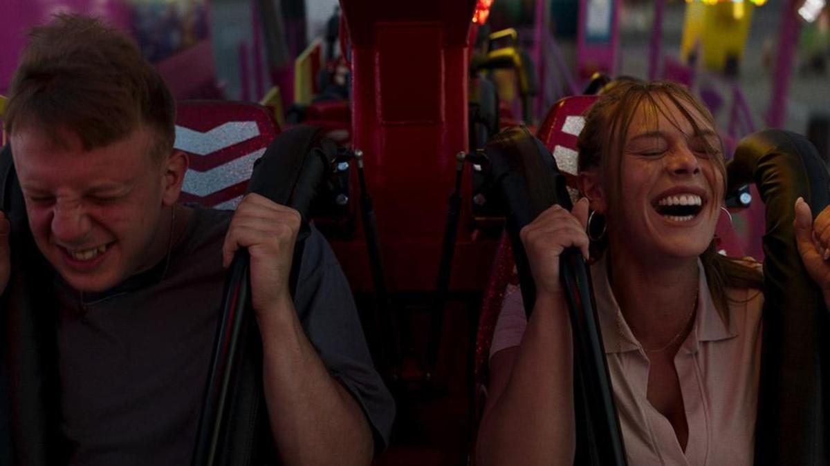 couple on roller coaster holding handles