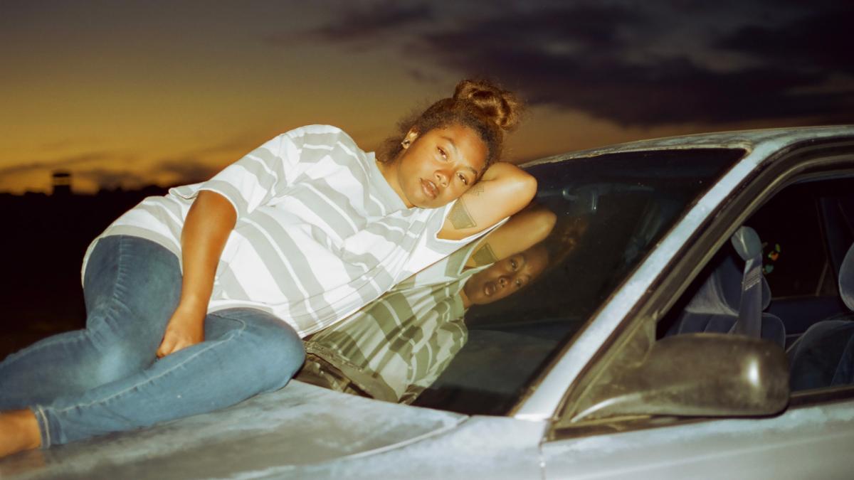 woman lying down on hood of car