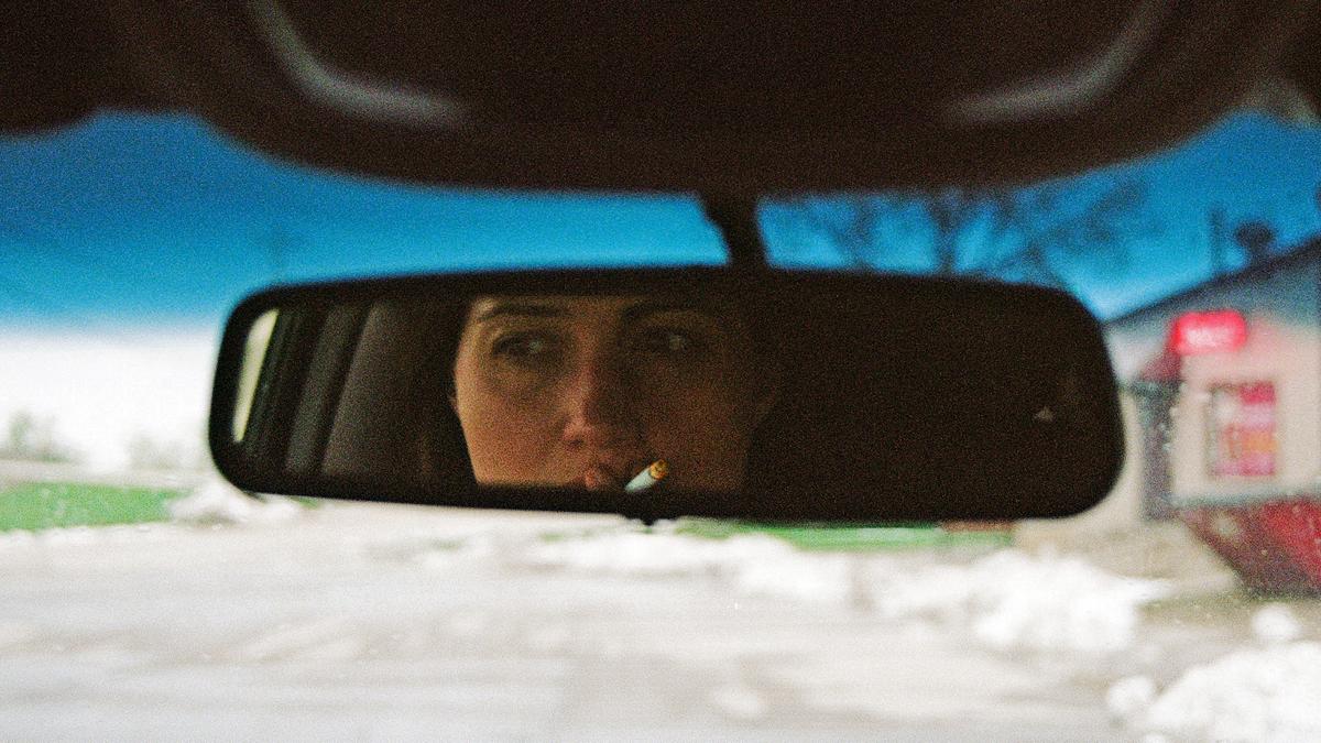 woman smoking cigarette in rearview mirror