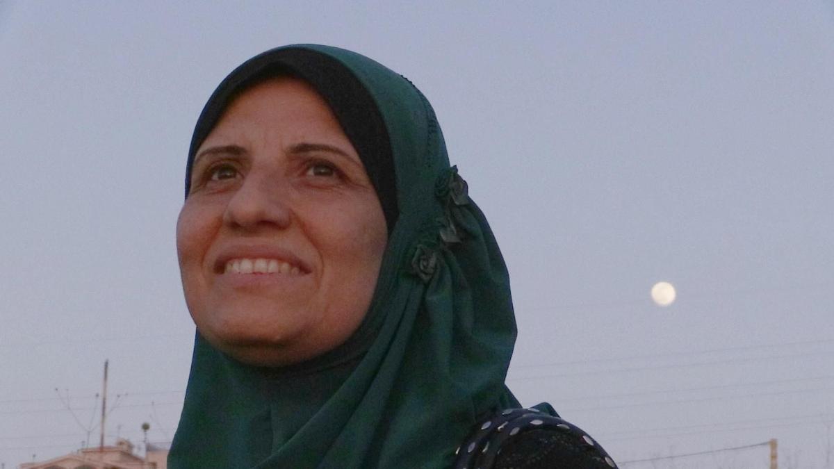 woman in hijab standing looking in distance with moon behind her