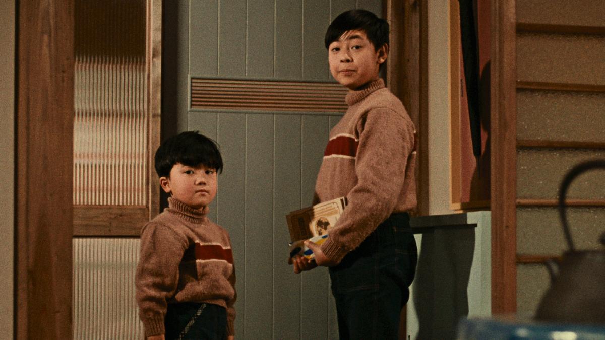 two young boys standing with books in arms in front of door turning around