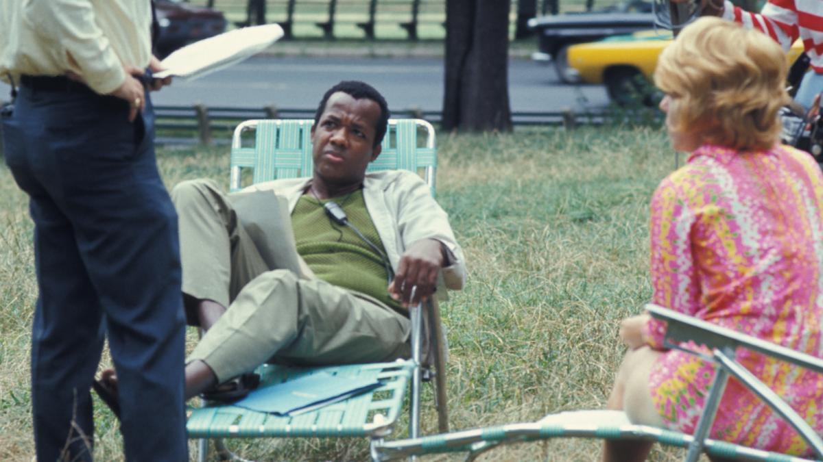 man sitting on lawn chair with other people scattered around him outside on grass