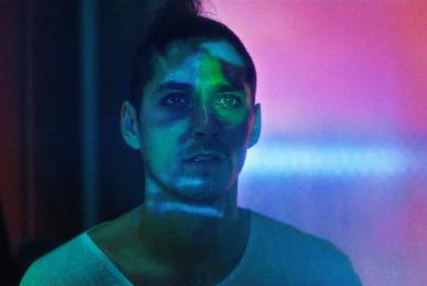 mans face with colorful lights on him and in background