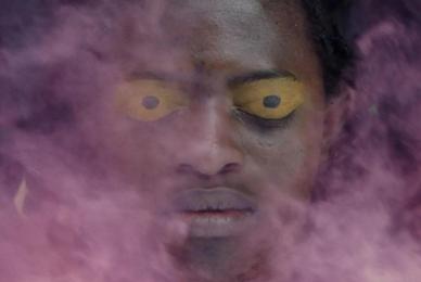 black man with yellow eyes and purple smoke enveloping face