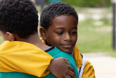 two young Black boys hugging outside