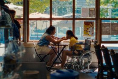 two women sitting at cafe table near window looking closely at each other