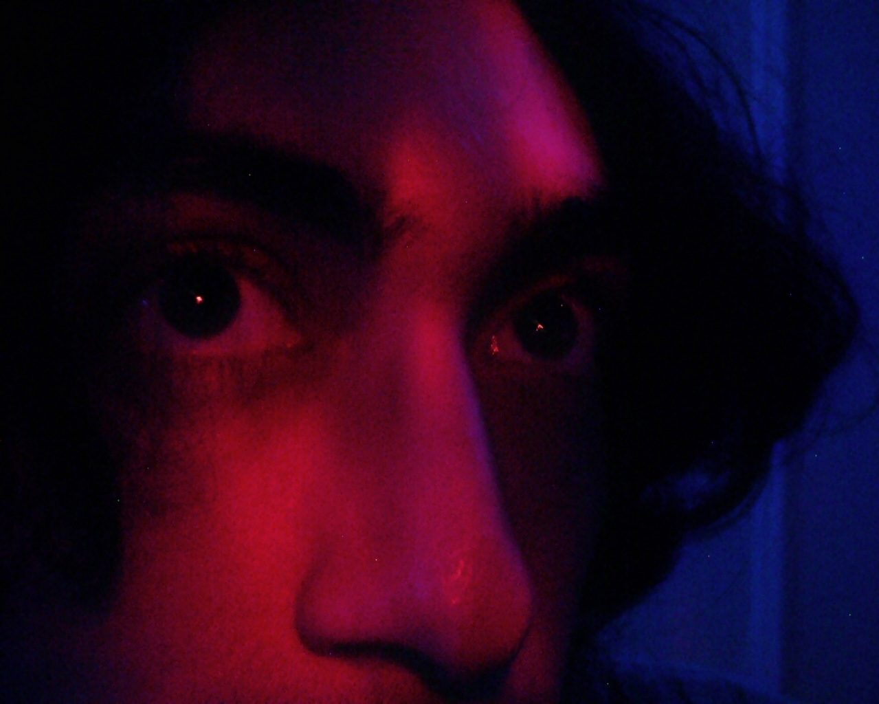 close up of man's face with pink and purple lighting