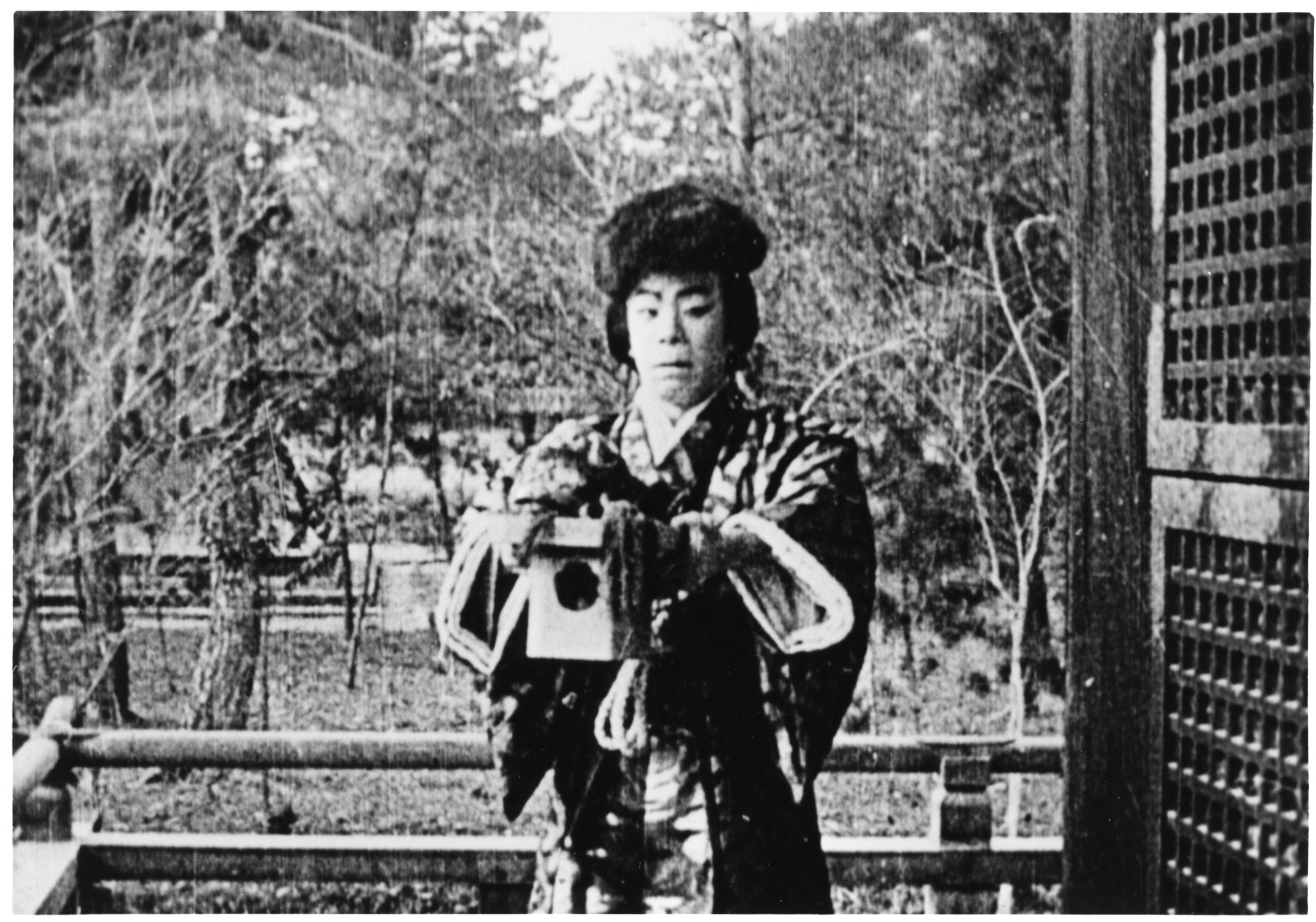 man in geisha robe standing holding object