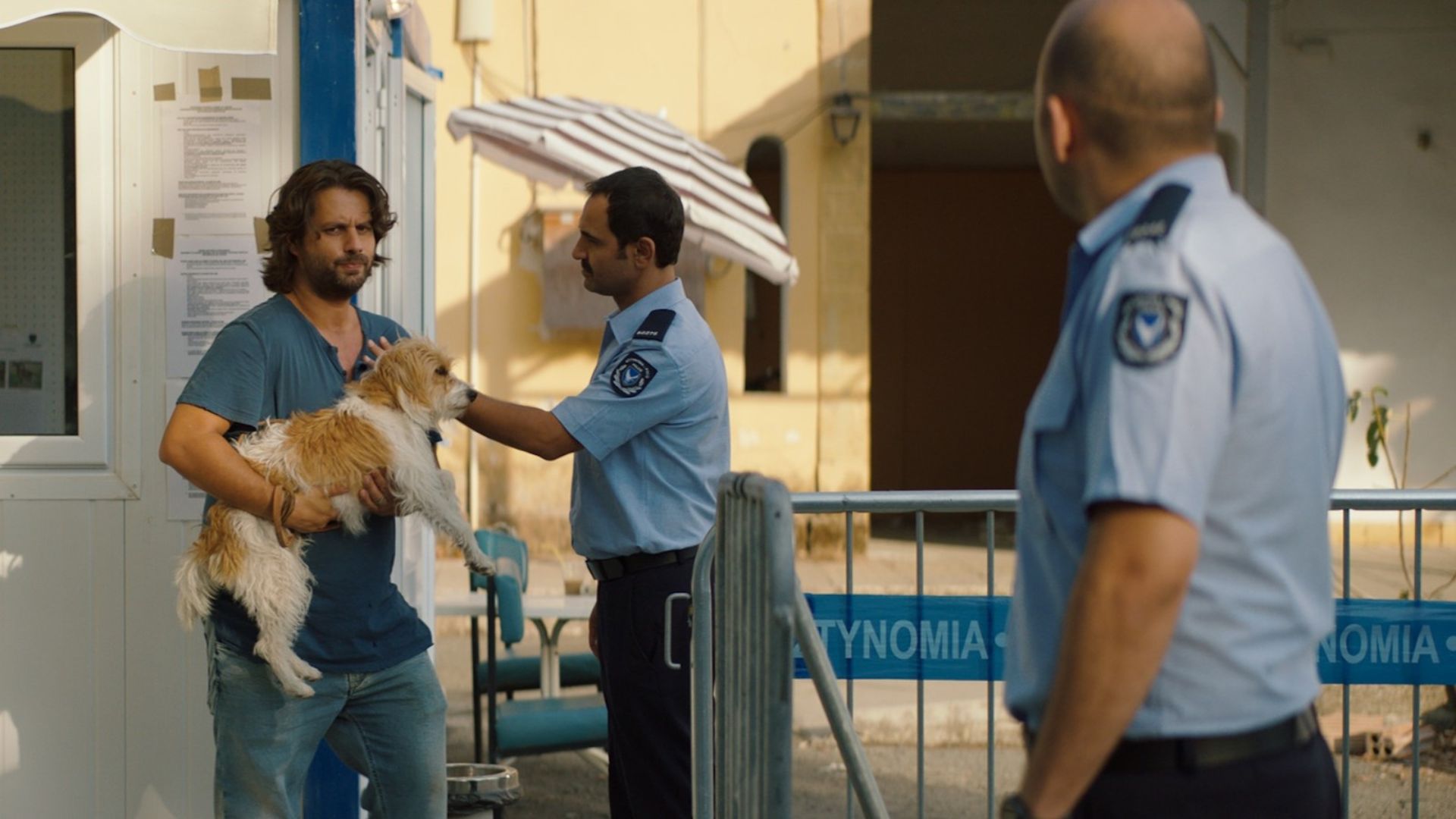 SMUGGLING HENDRIX, 2018, man holding small dog with police officers investigating
