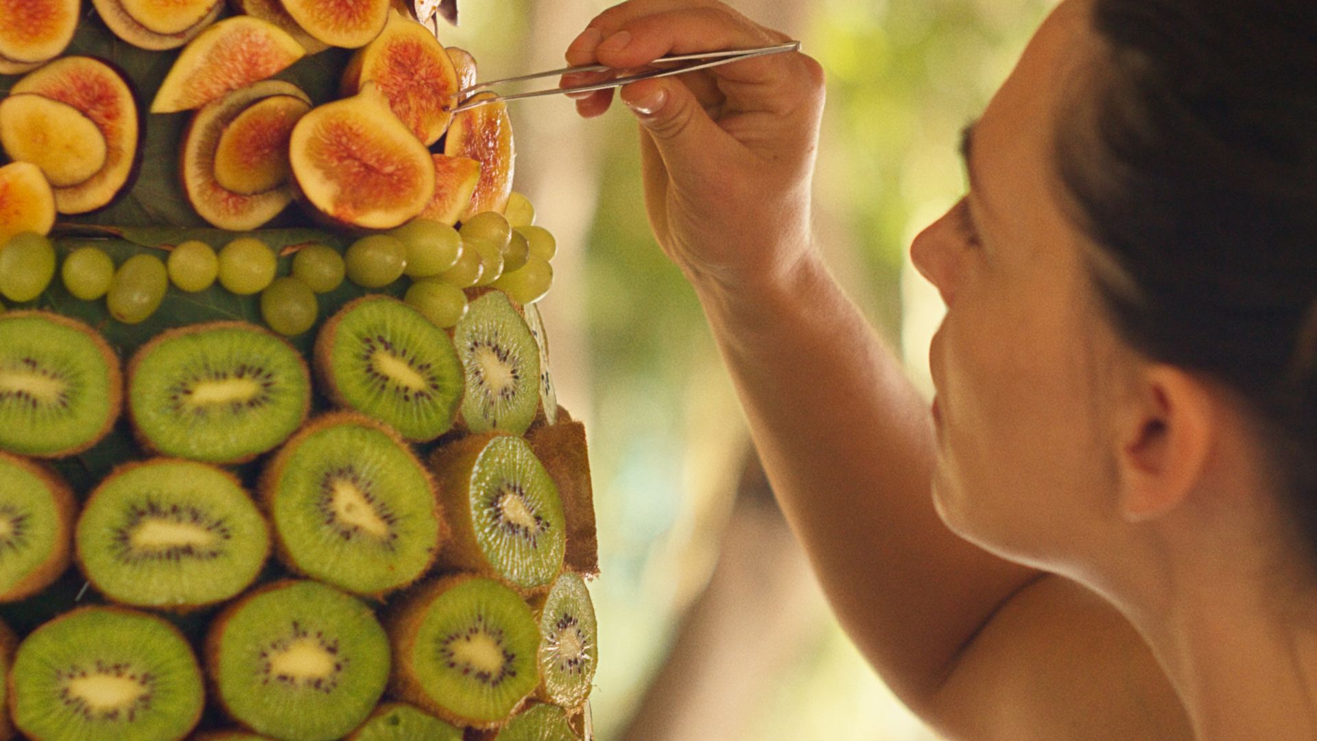 A SUMMER PLACE, woman working on fruit sculpture 
