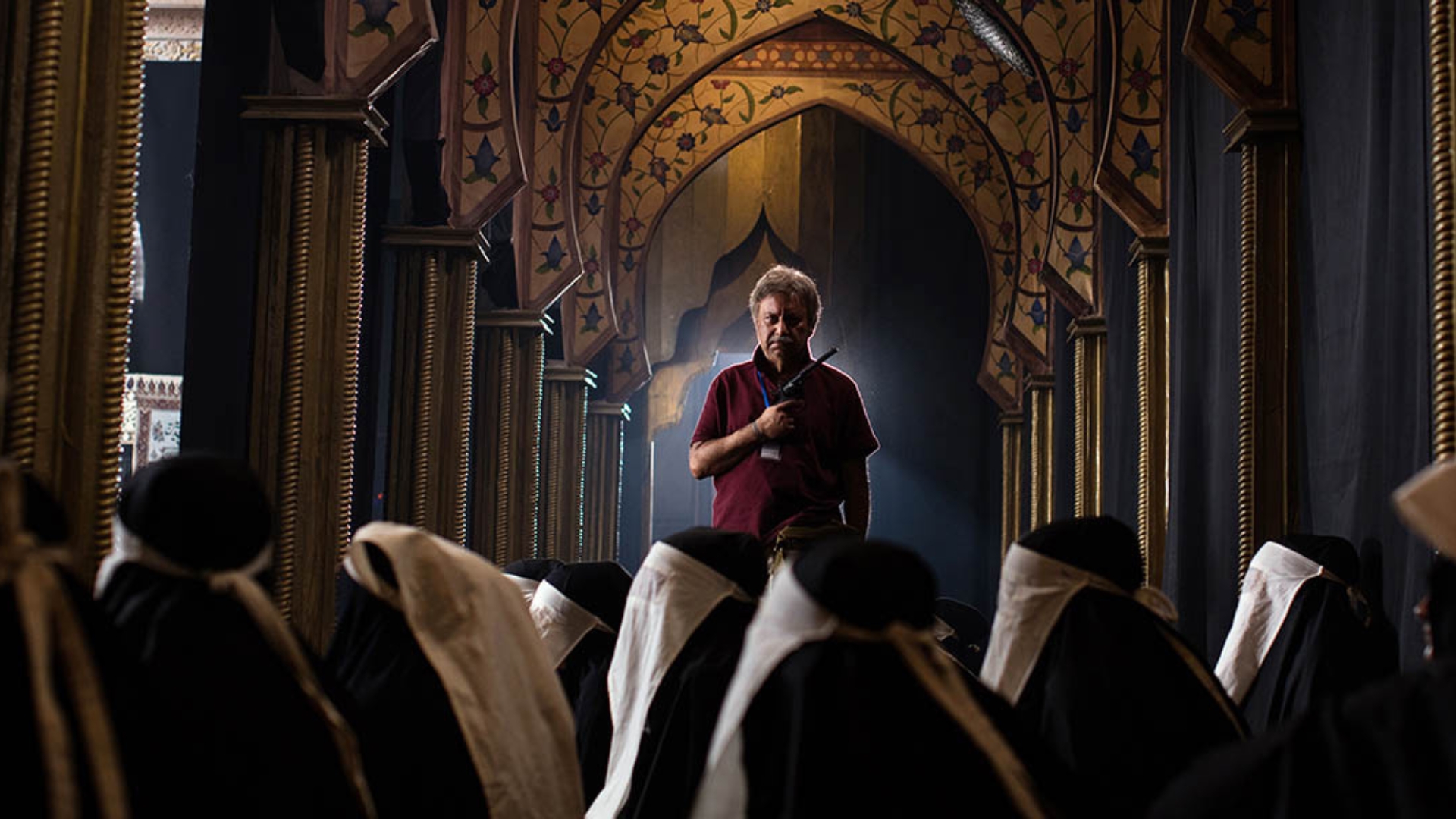 BLACK RABBIT WHITE RABBIT, 2025, man standing in front of seated group inside large house of worship