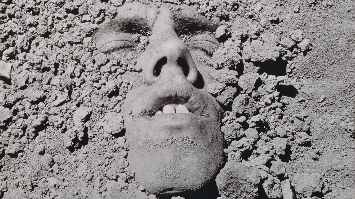 Person's face pertruding out of gravel