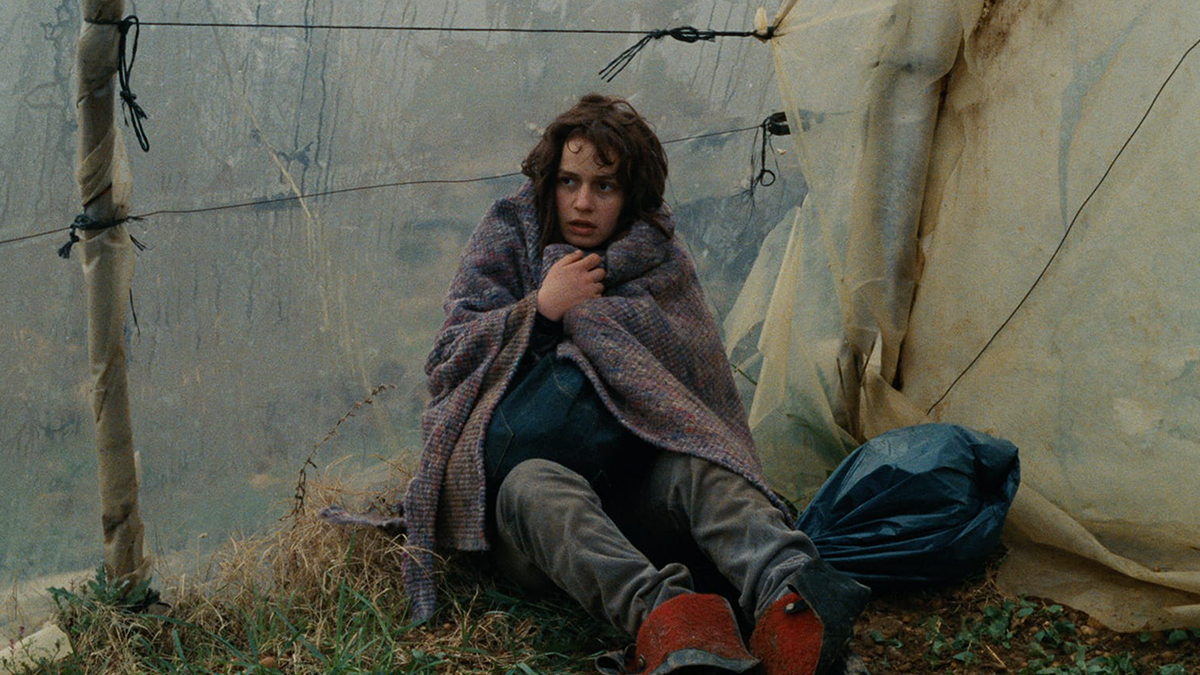 Person wrapped in a blanket, looking disheveled 