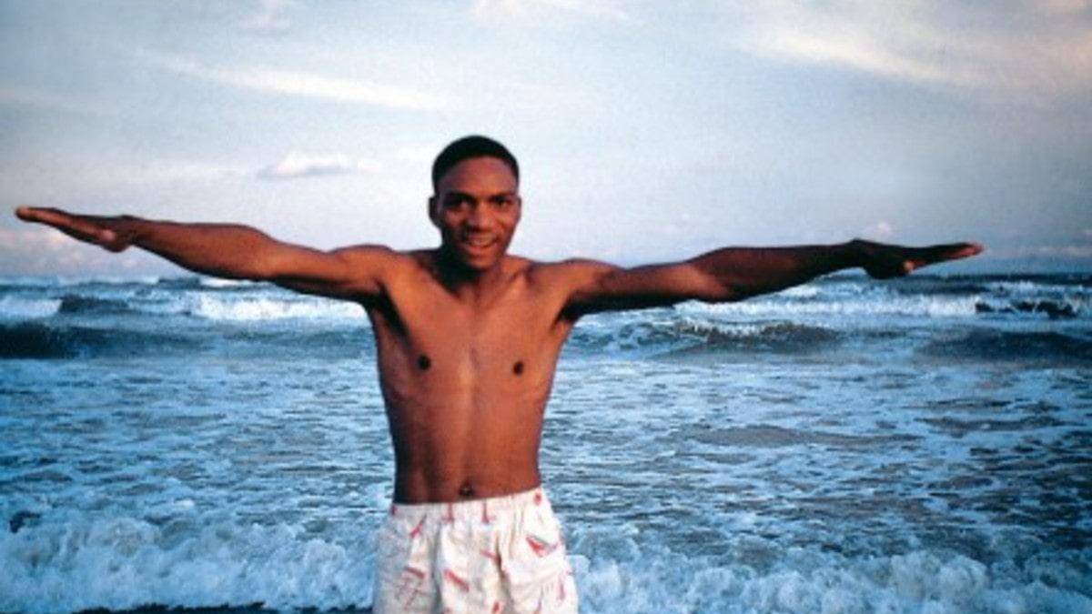 man with outstretched arms in front of ocean
