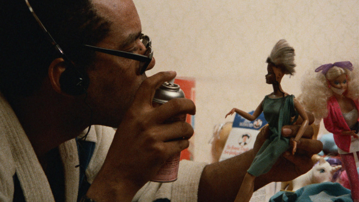 man spray painting holding doll