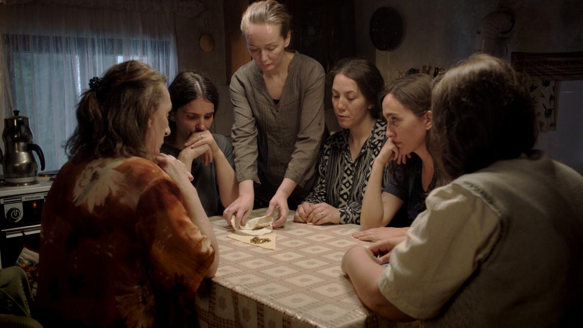 people looking at piece of food gathered around table
