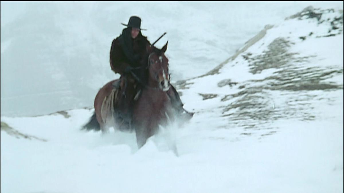 man riding horse through snow