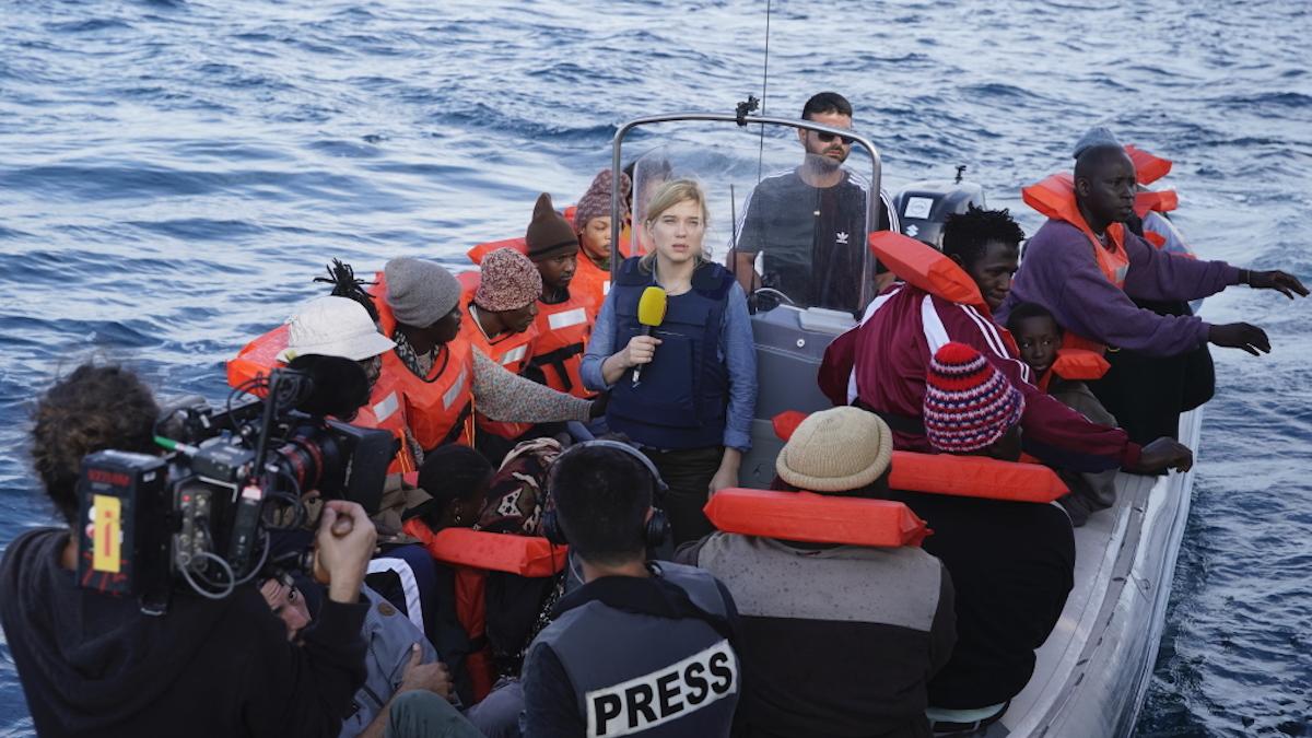woman on raft with men and reporters in life vests