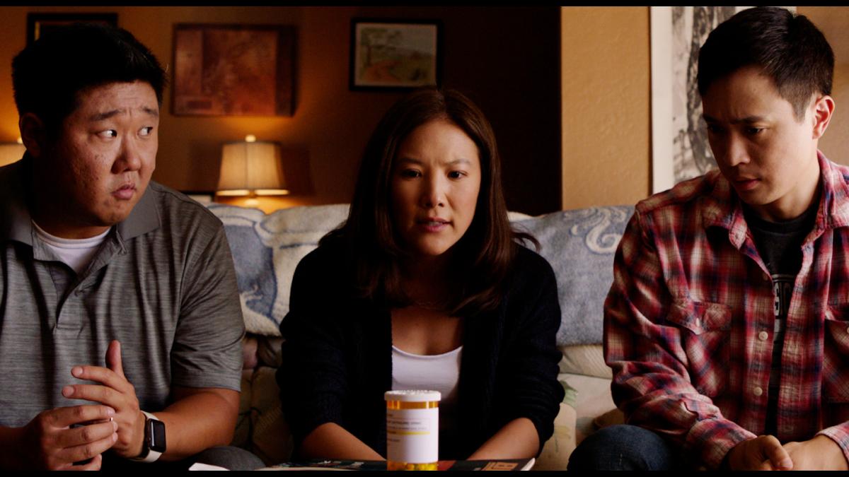 two men and one woman sitting on couch looking at each other