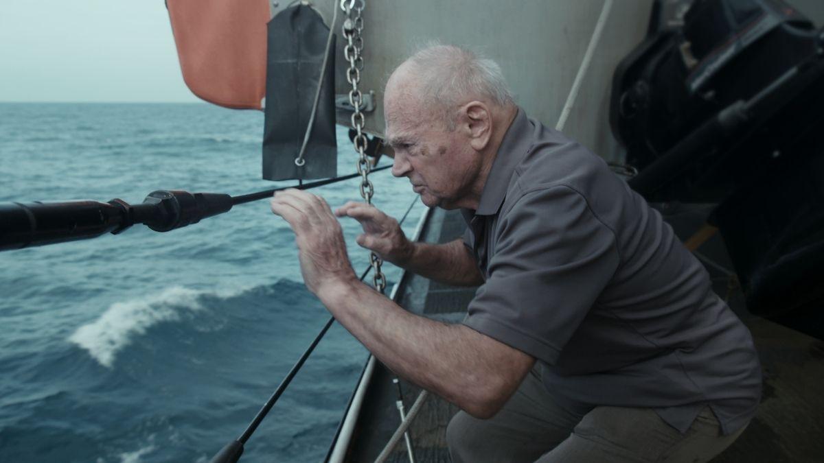 man on boat looking into water with spyglass