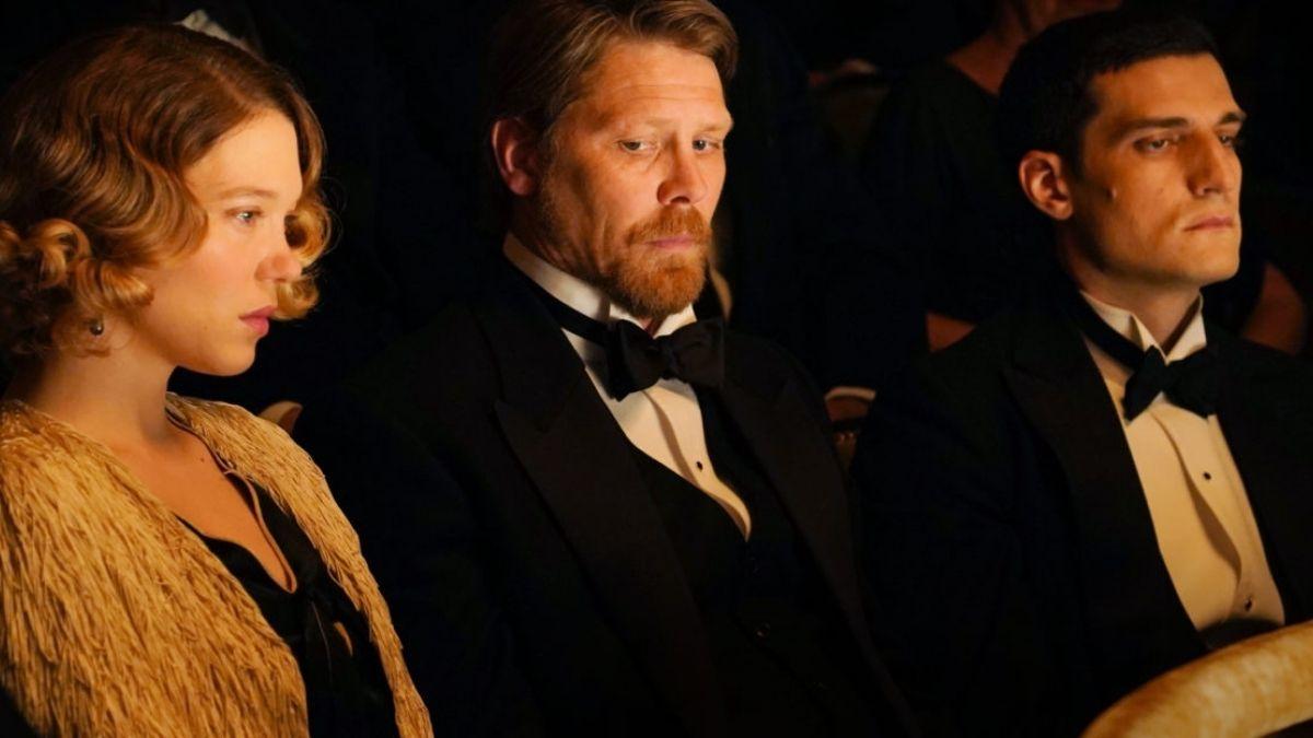 woman and two men sitting in theatre seats in formal wear