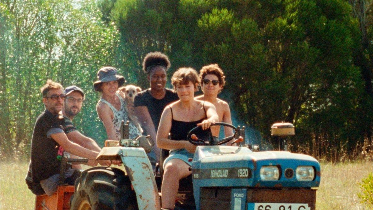six people riding on tractor in field
