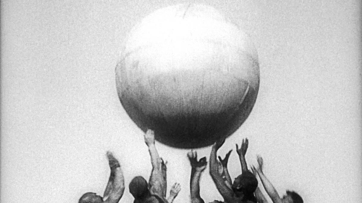 men standing with arms outstretched balancing large ball