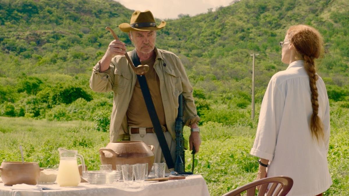 man and woman on hillside at a meal with man drinking from soup ladle 