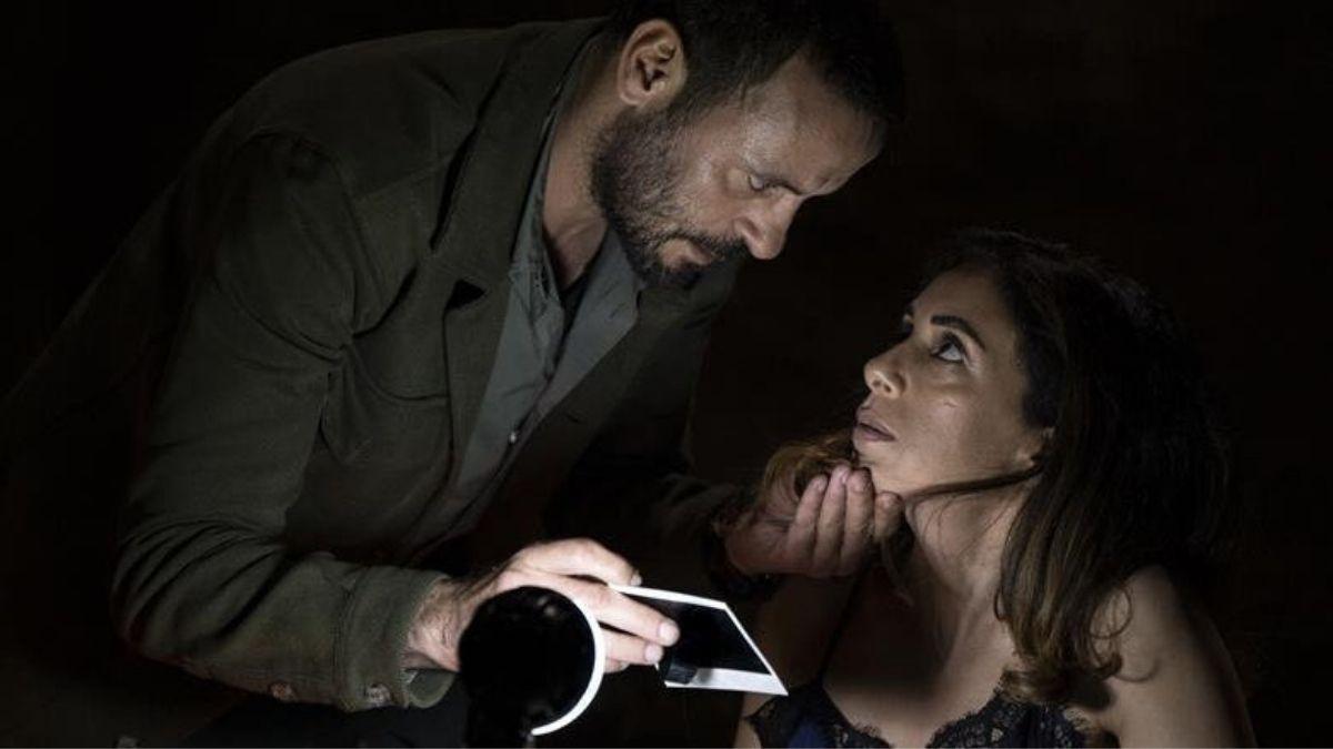 man and woman in dark with man holding light and woman's chin