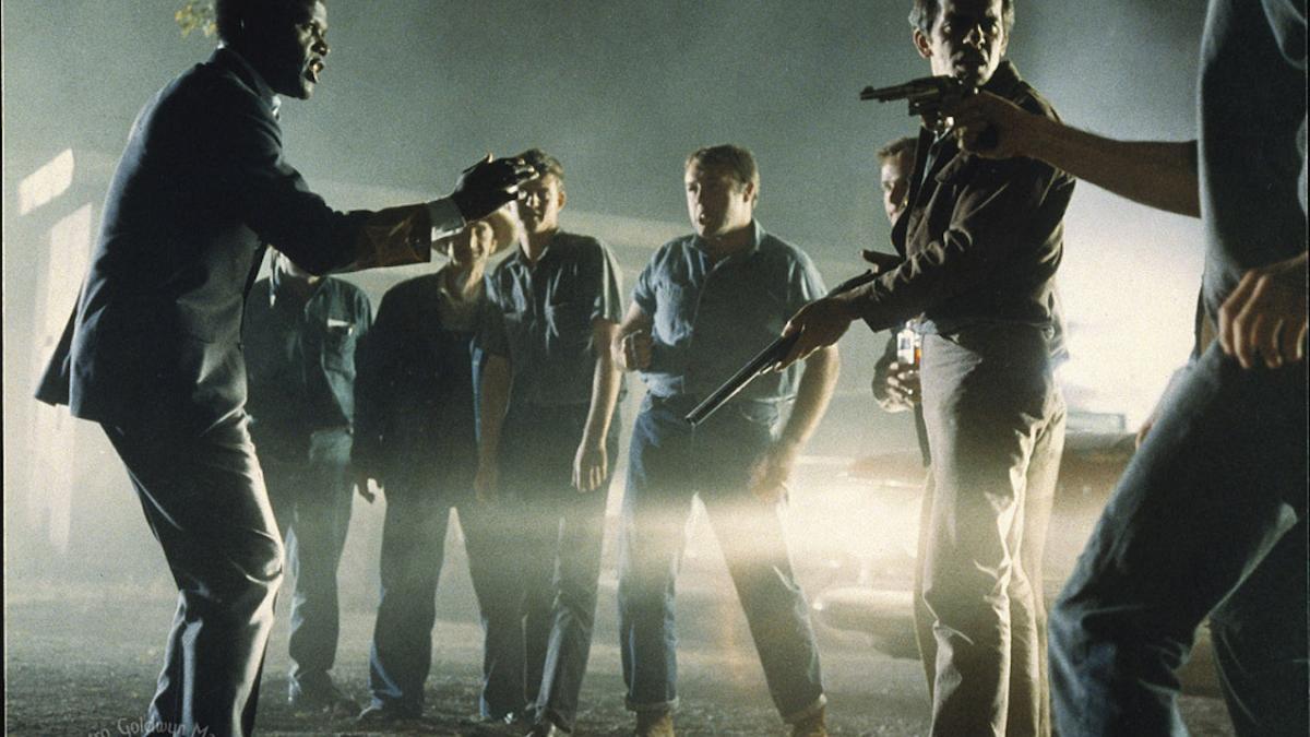 men gathered around with weapons cornering a man at night