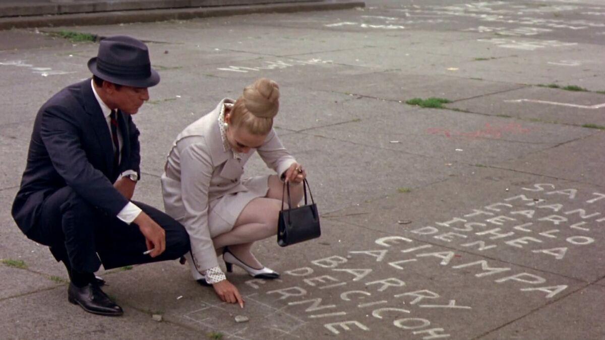 man and woman kneeling on sidewalk while woman points at chalk writing
