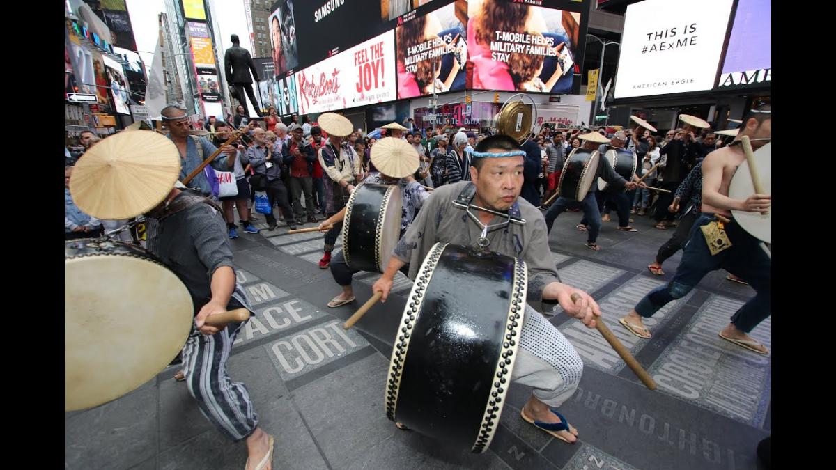 group of men playing drums while walking down city street
