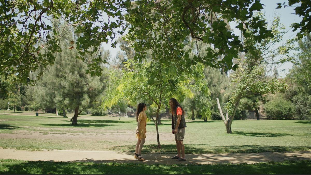 man and woman standing facing each other in park