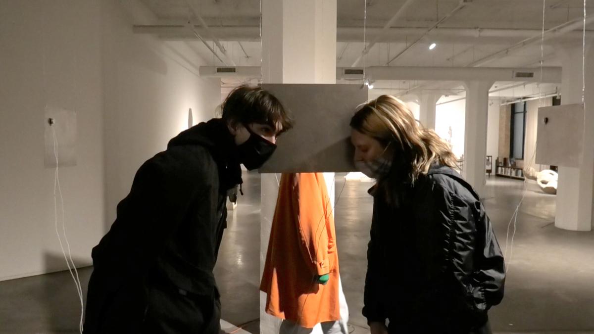 two people facing each other in gallery with heads bowed