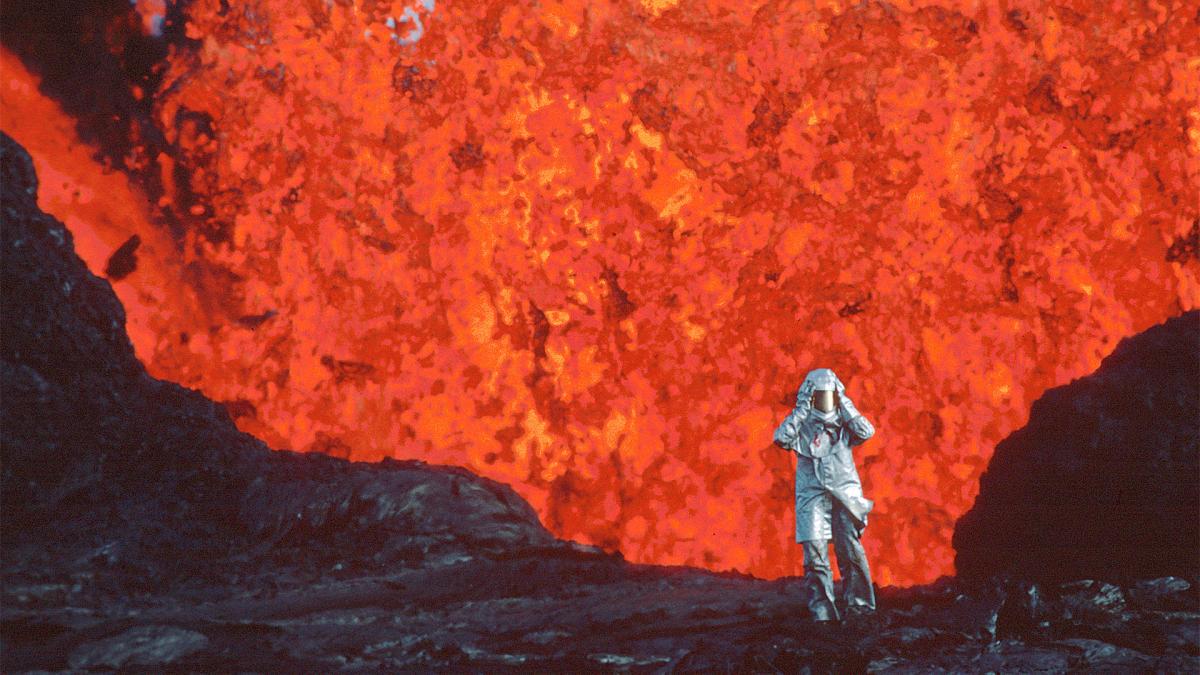 person standing in front of lava in a volcano