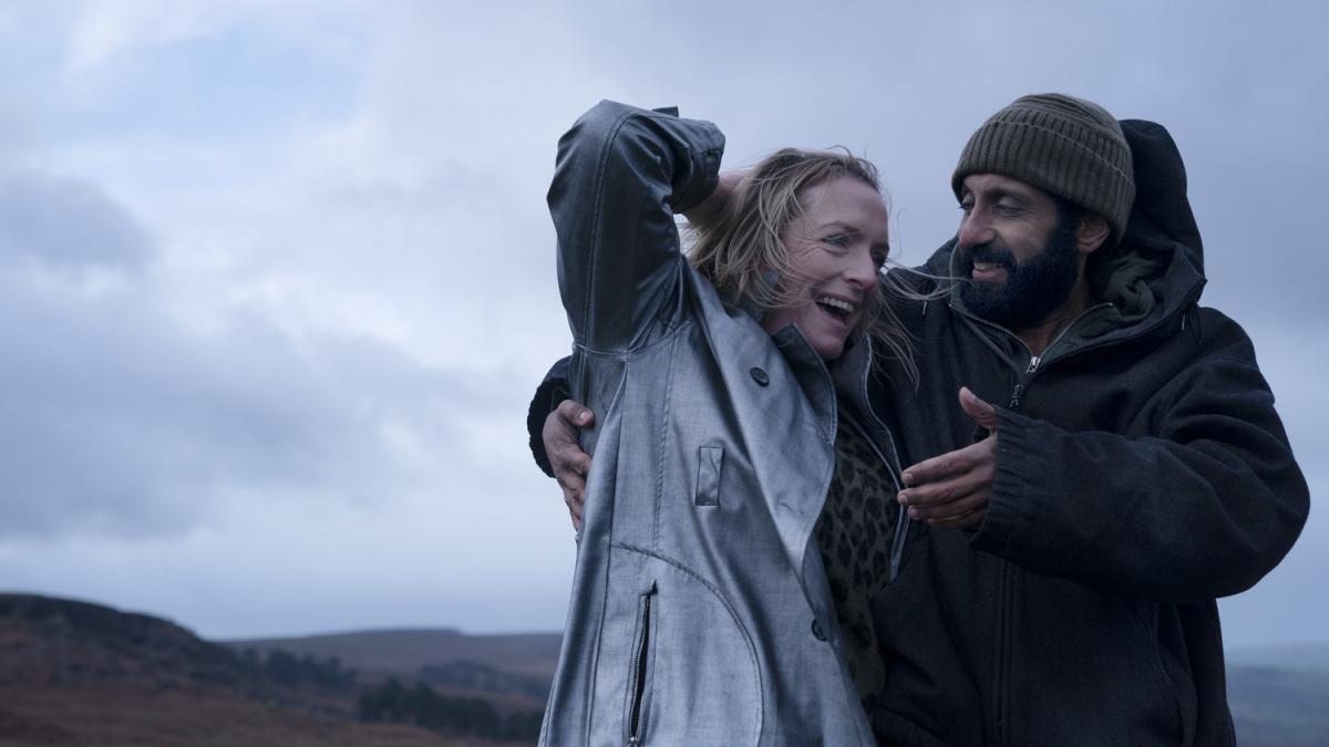 couple hiking on a hill wearing rain jackets with arms around each other