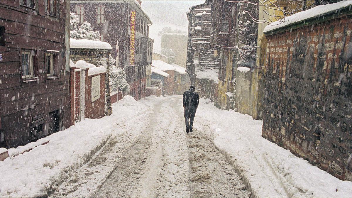 man walking through snowy city street