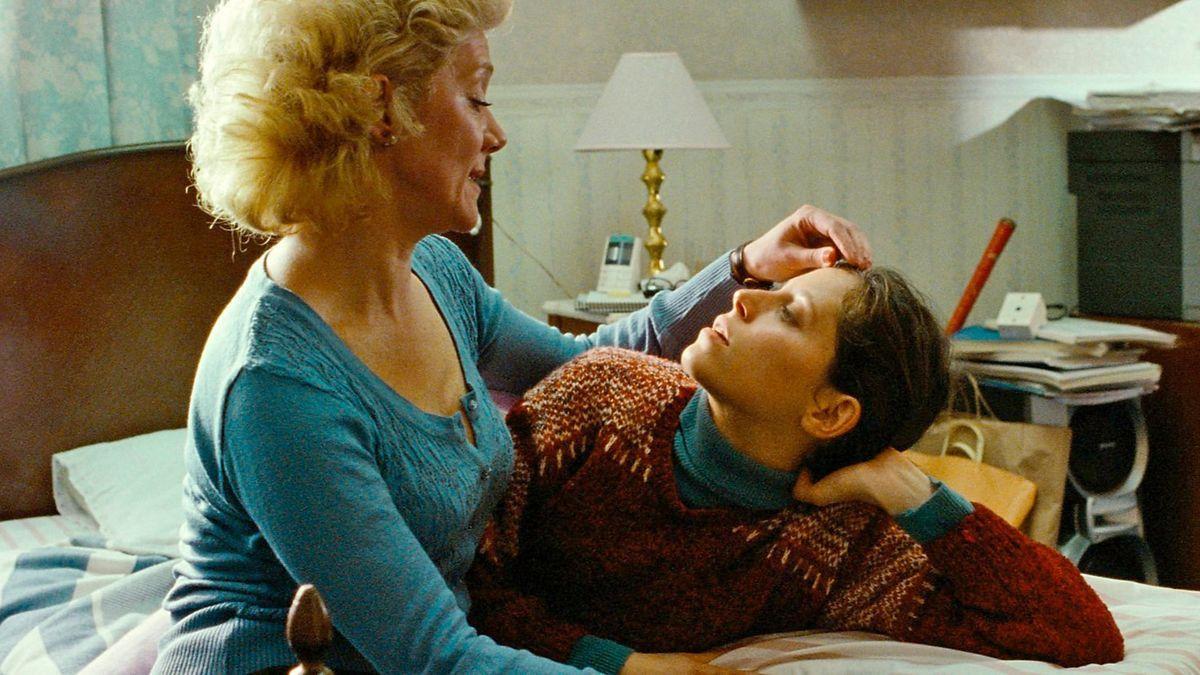 woman touching boy's hair on bed