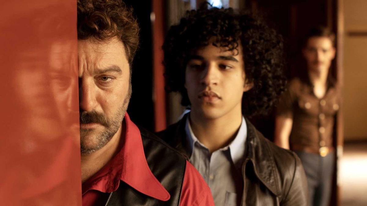 man staring behind wall with two other people behind him