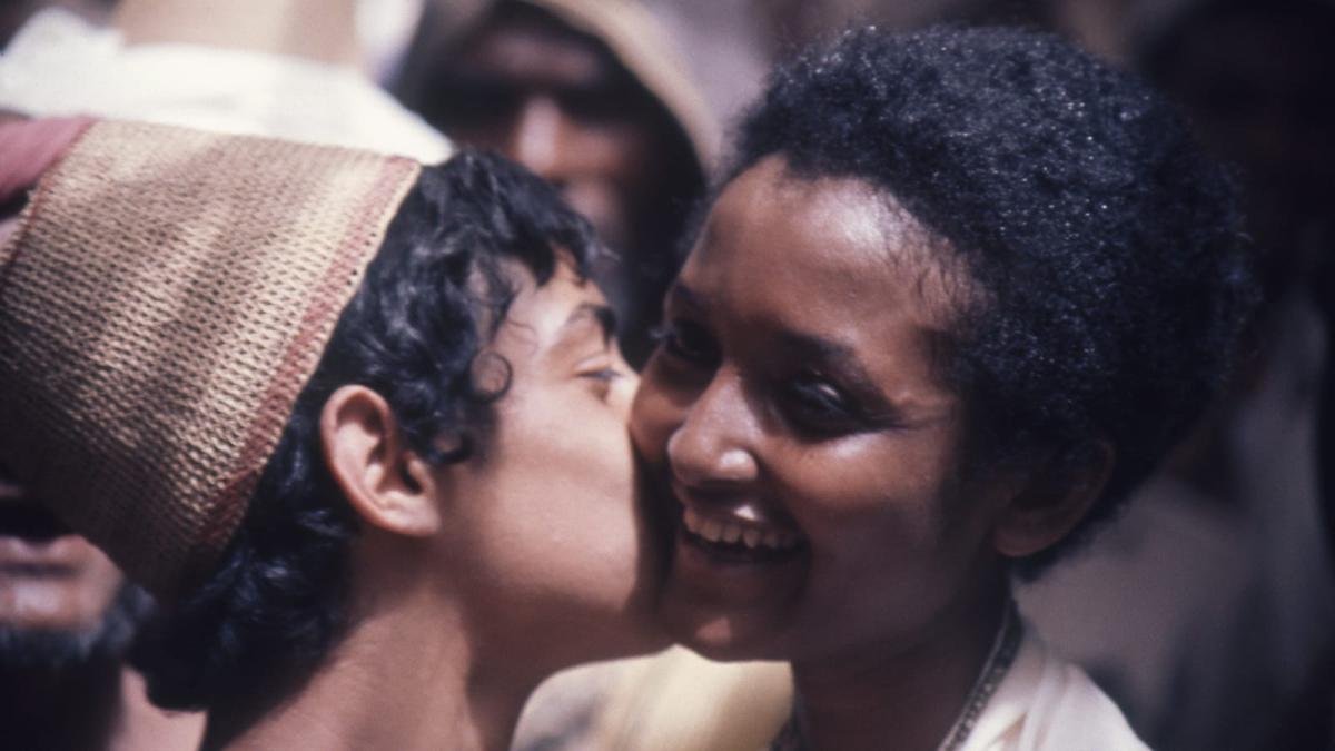 boy in woven cap kissing a woman on the cheek