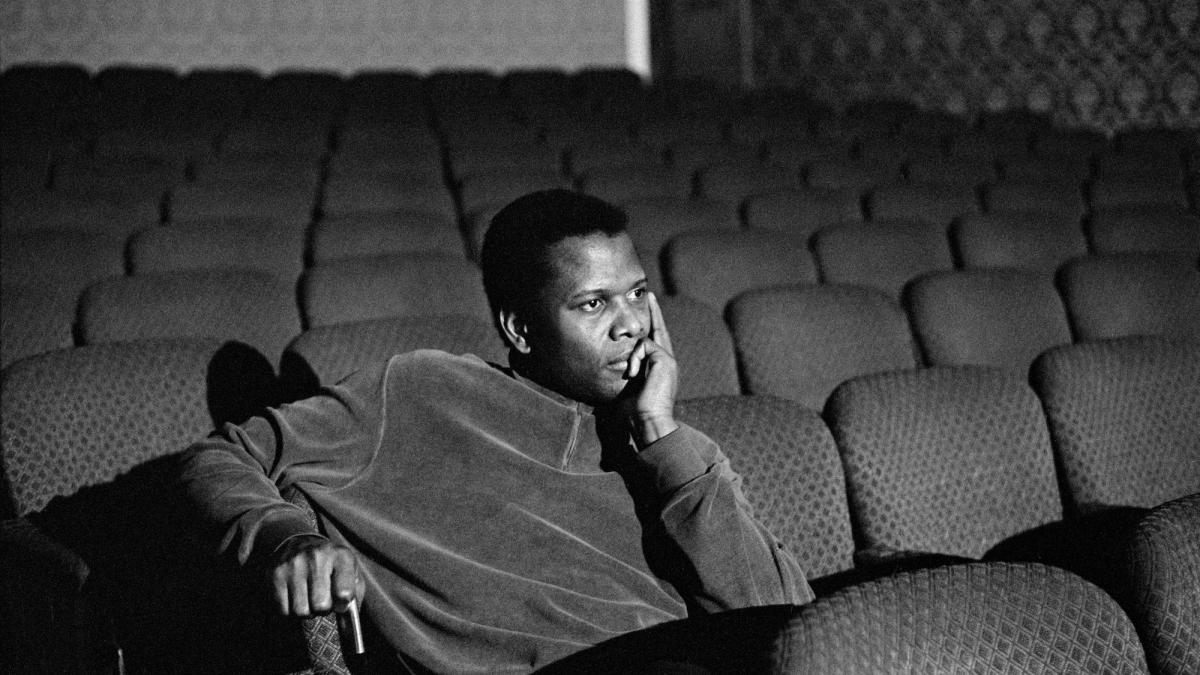 man sitting in empty theater with face resting on hand