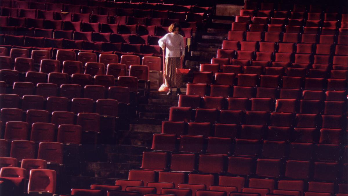 woman standing in aisle of empty movie theater