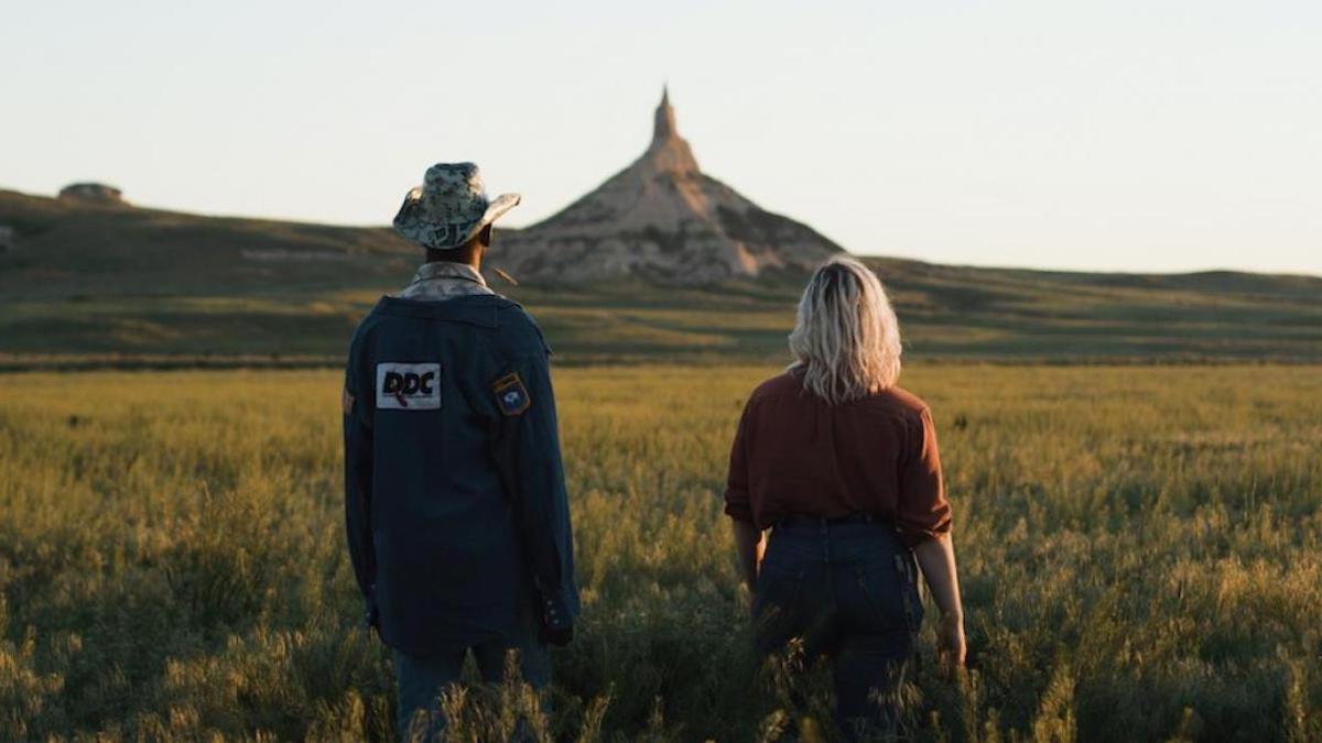 man and woman standing in field looking ahead