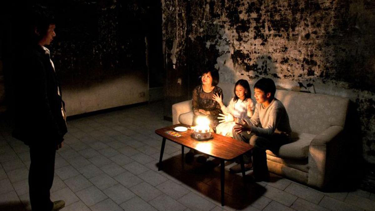 people sitting in dark room on couch with candles lit in front