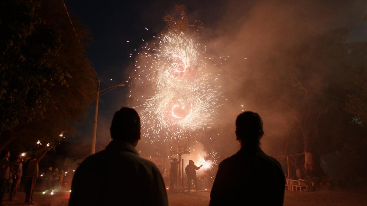 silhouettes of two people looking up at fireworks and sparks in the air
