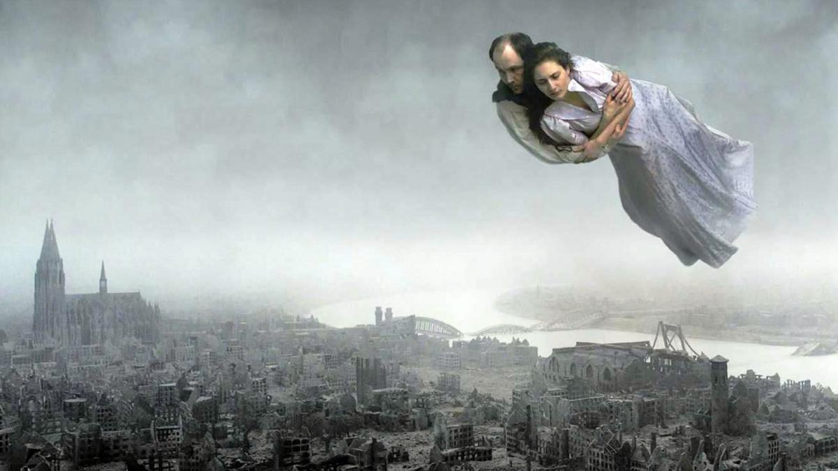 man holding woman in nightgown flying over sky with dark city skyline in background